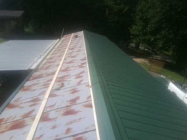 Old rusted panels beside newly installed green metal roofing — Wind Damage Roof Repair by Roofing Brothers in Dennis Port