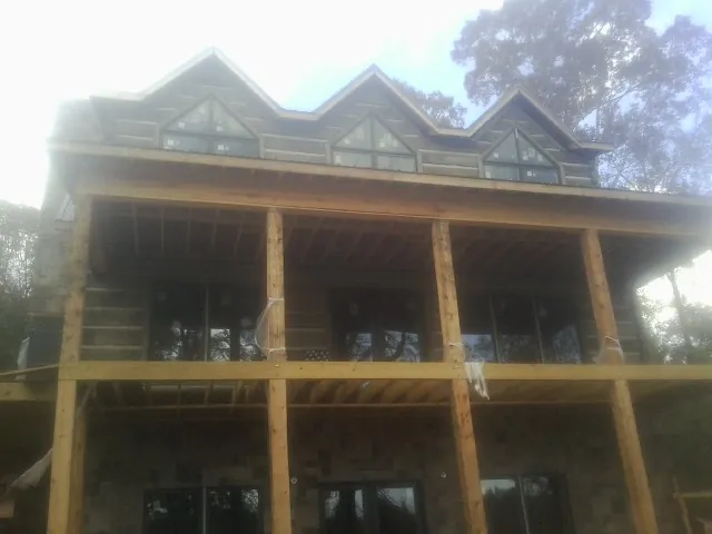 Dormers and porch framing on a large log home under construction — Roof Coating work by our crew in Dennis Port