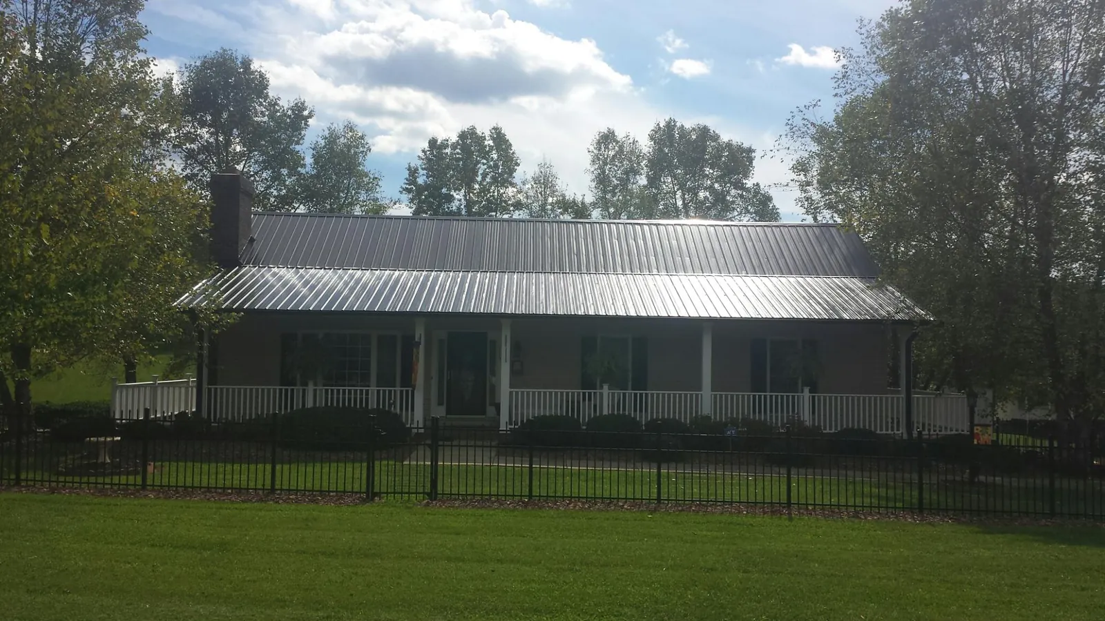 Gray metal roof on a brick ranch with a full width front porch — Gutter Guard Installation work by our crew in Dennis Port