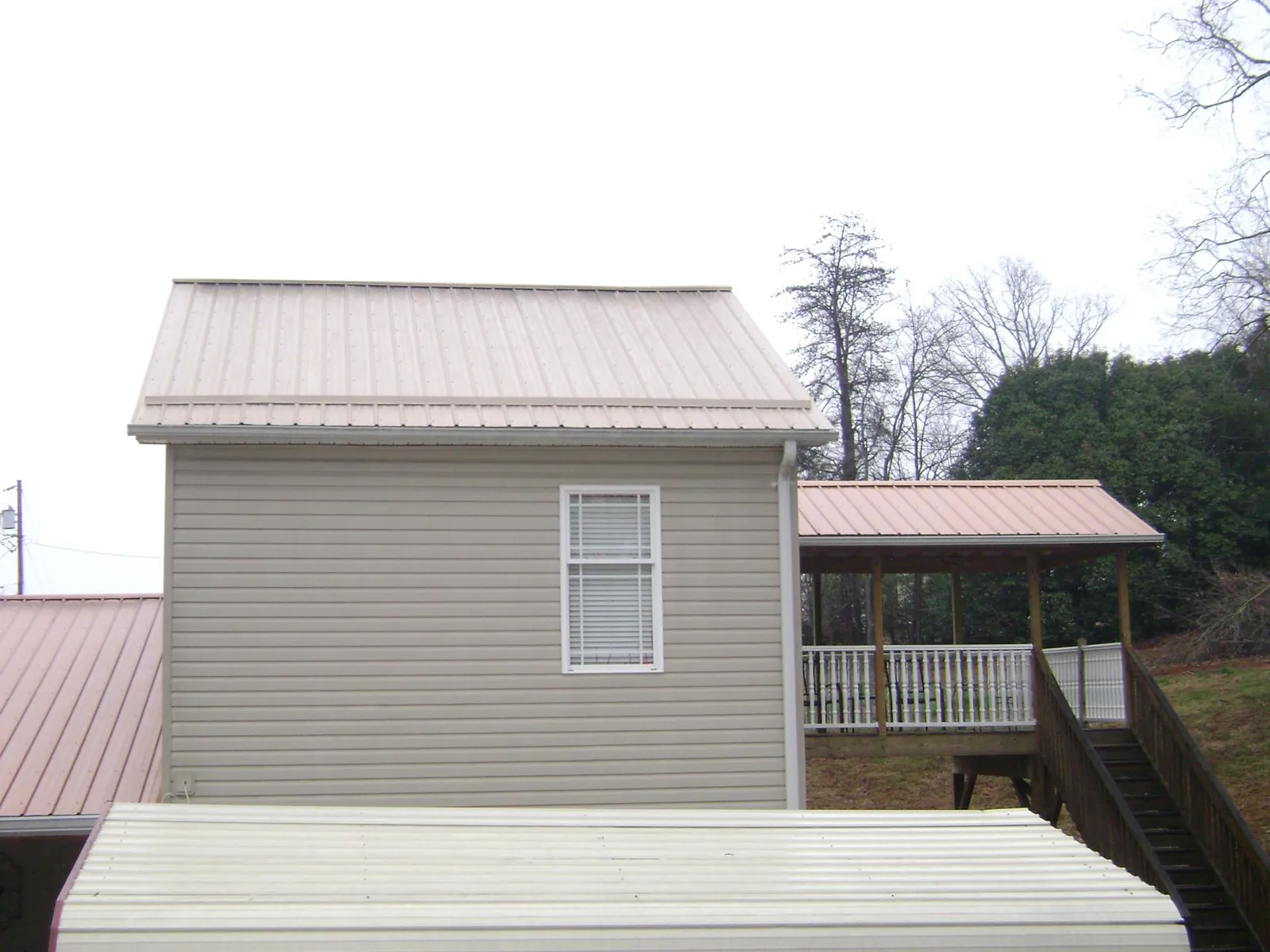 Tan metal roofs on a two story addition and attached porch, from a Roof Replacement job in Dennis Port